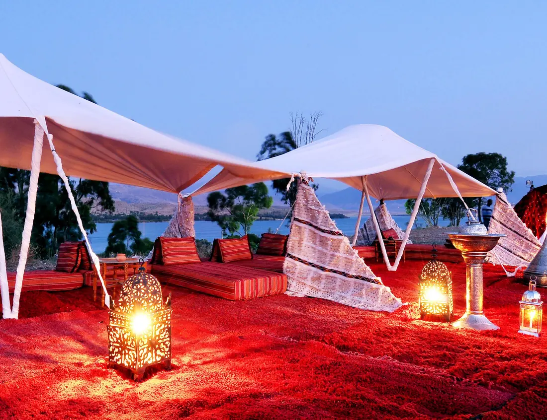 Tents and lanterns of a desert camp at dusk